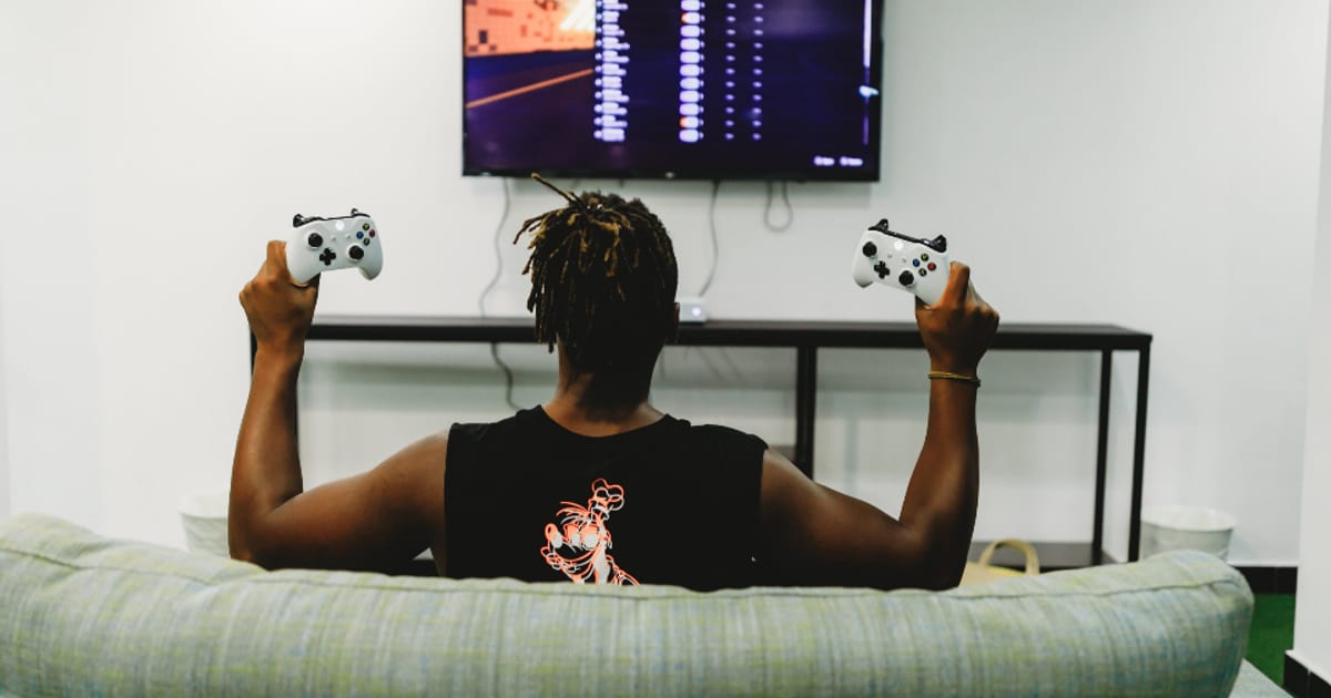 A player on a sofa holding a controller in front of a screen