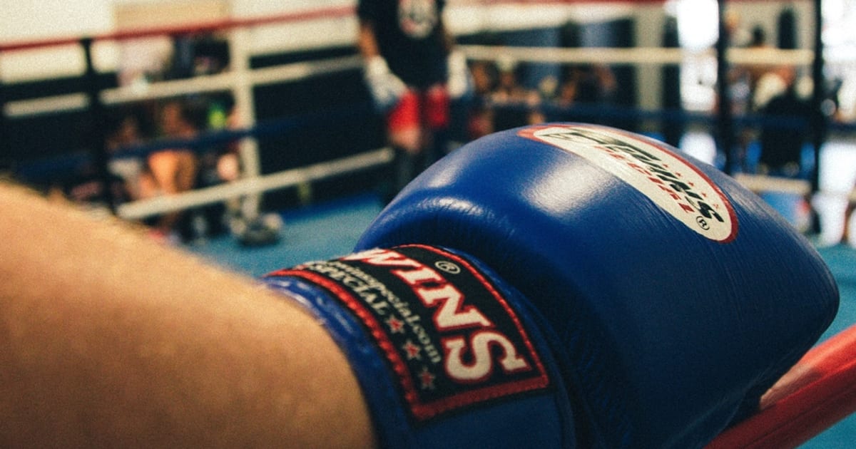 A blue boxing glove in close-up beside a ring