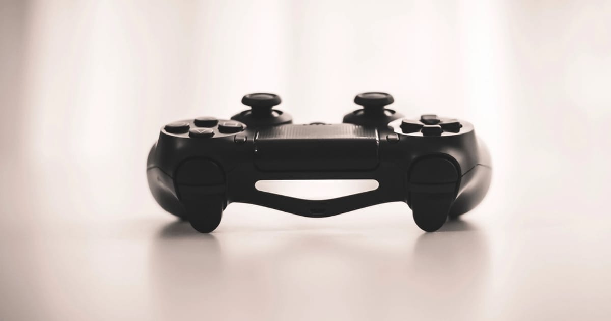 A black game controller on a plain white table