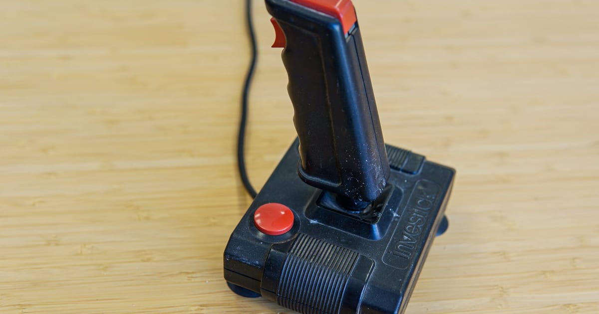 A retro arcade joystick on a wooden floor